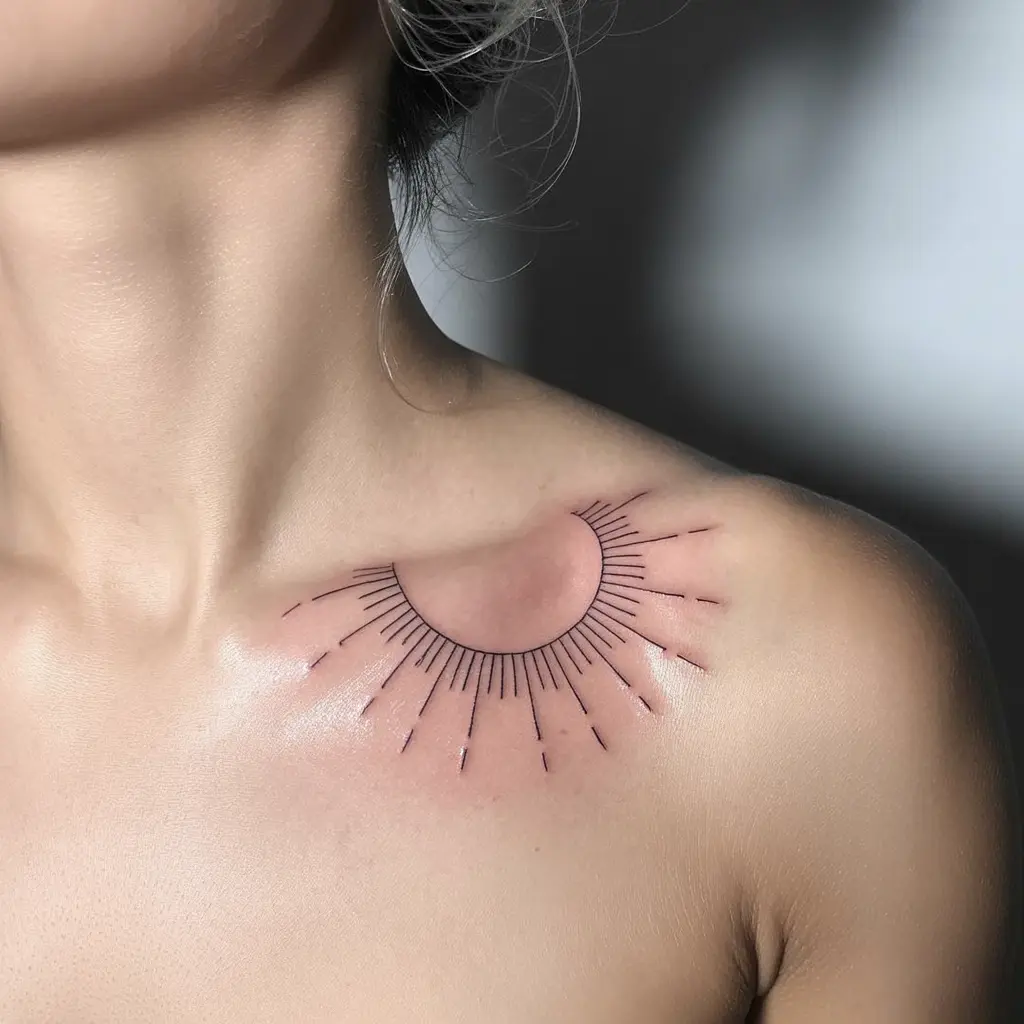 Ink Halo collar bone tattoo with fine-line sunburst rays arching naturally along the collar bone, symbolizing positivity and light.